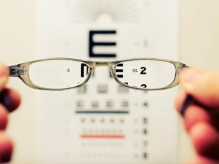 Eye glasses looking at eye chart on wall. Photo by David Travis on Unsplash