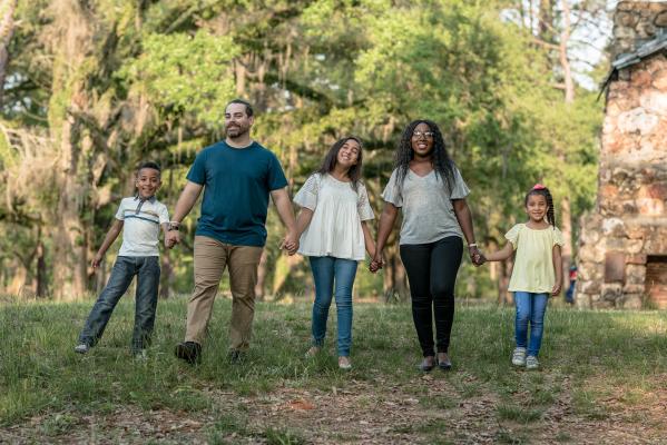 Family of five standing near trees holding hands during daytime. Photo by Blake Barlow on Unsplash