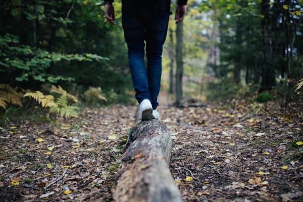 Man walking on log in forest. Photo by Jon Flobrant on Unsplash