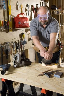 Man in a workshop sanding. St. John Ambulance first aid kit in the background.