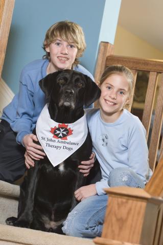 Girl and boy on stairs posing with St. John Ambulance therapy dog.