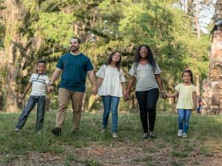 Family of five standing near trees holding hands during daytime. Photo by Blake Barlow on Unsplash