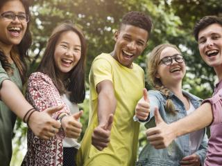 Group of youth smiling and giving thumbs up.